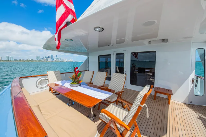 Slide: The Image of Luxurious 1998 Burger Raised Pilothouse yacht deck with dining area, ocean view, and city skyline. - 48