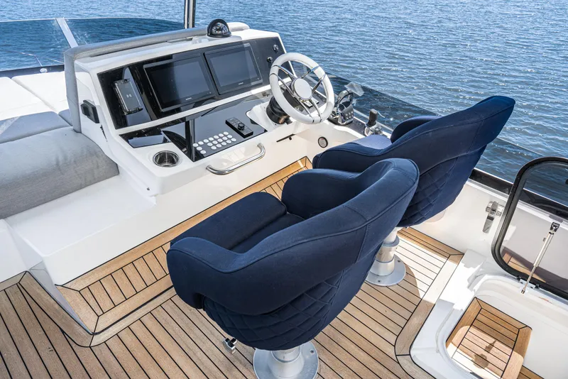 Slide: The Image of Sunseeker Manhattan 55 2021 yacht helm station with blue seats and modern controls. - 30