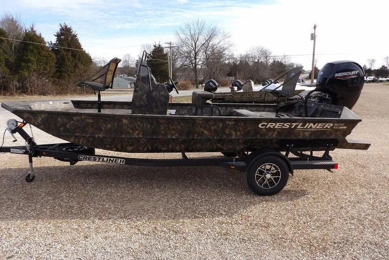 Slide: The Image of 2026 Crestliner 1870 Retriever FCC boat on trailer, camo design, parked outdoors. - 3