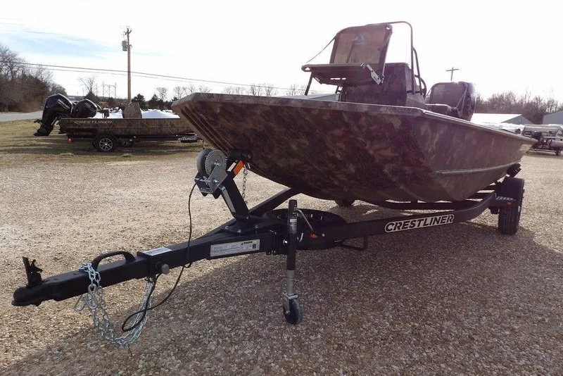 Slide: The Image of 2026 Crestliner 1870 Retriever FCC boat on trailer, camo design, parked outdoors. - 35