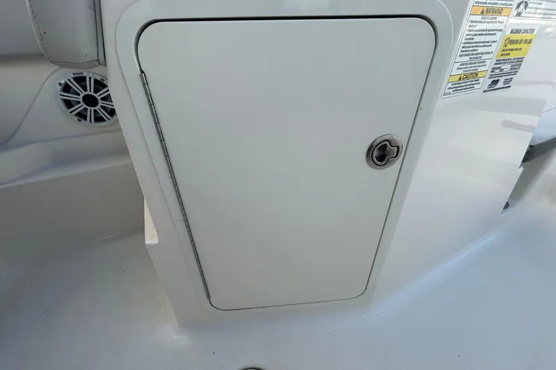 Slide: The Image of 2020 Sea Ray SPX 210 Outboard storage compartment with lock and safety labels. - 66