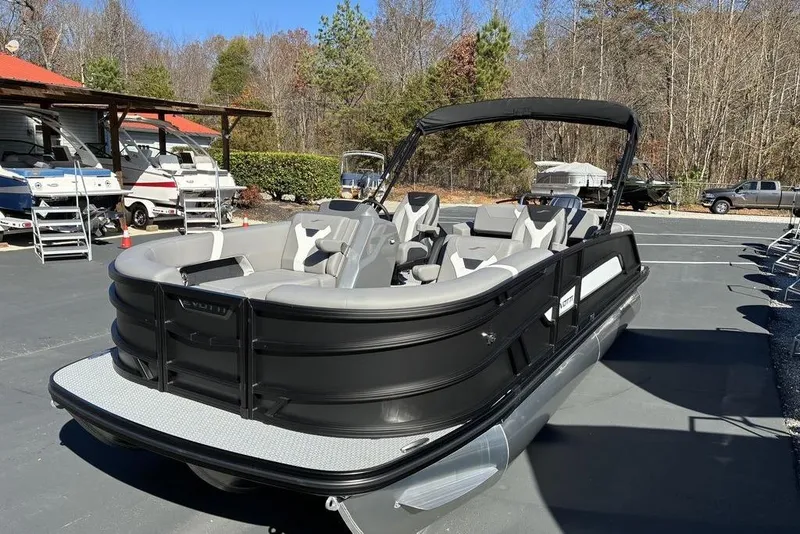 The Image of 2026 Evotti 521CS pontoon boat in a parking lot, surrounded by trees and other boats. - 0