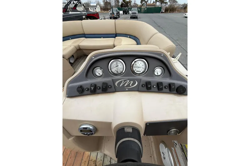 Slide: The Image of 2017 Manitou 22RF boat dashboard with gauges and beige seating. - 12