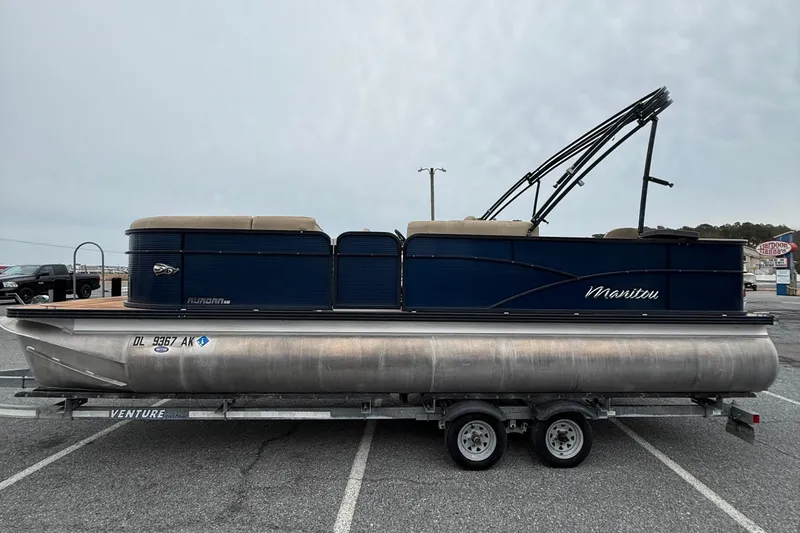 Slide: The Image of 2017 Manitou 22RF pontoon boat on trailer, blue and silver design, parked outdoors. - 5