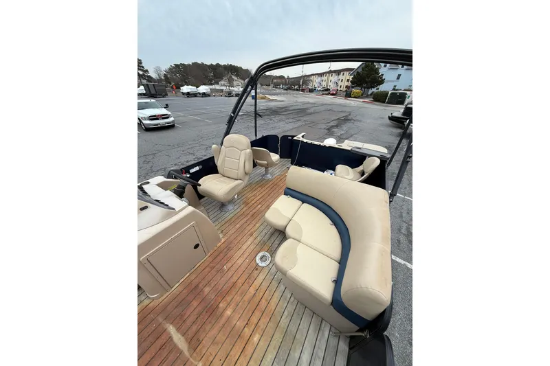 Slide: The Image of 2017 Manitou 22RF pontoon boat with beige seating and wooden deck in a parking lot. - 9