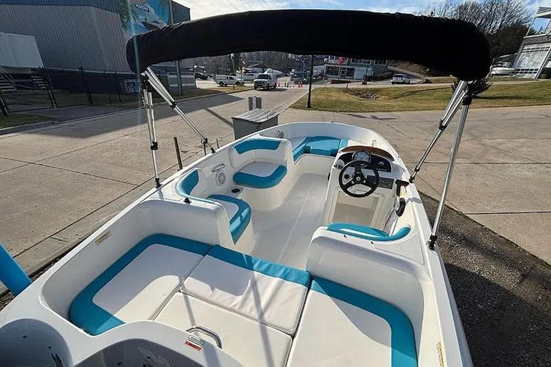 Slide: The Image of 2021 Bayliner Element E16 boat with blue and white seating, docked outdoors. - 16