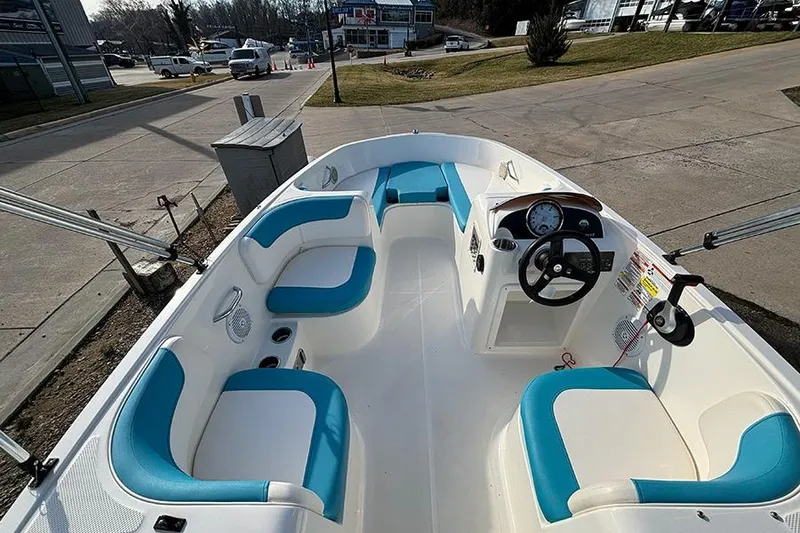 Slide: The Image of 2021 Bayliner Element E16 boat with blue and white seating, docked on a sunny day. - 17