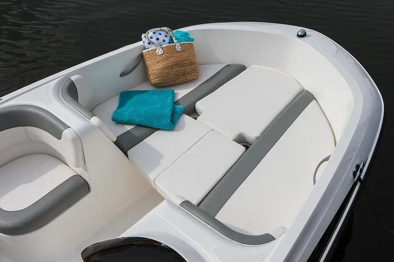 Slide: The Image of 2021 Bayliner Element E16 boat interior with blue and white seating, docked outdoors. - 7