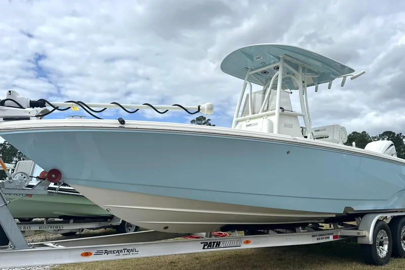 The Image of 2024 Pathfinder 2400 TRS boat on trailer, light blue hull, cloudy sky background. - 0