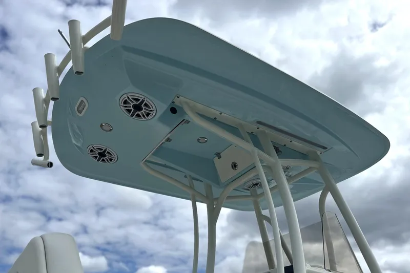 Slide: The Image of 2024 Pathfinder 2400 TRS boat T-top with rod holders and speakers against cloudy sky. - 6