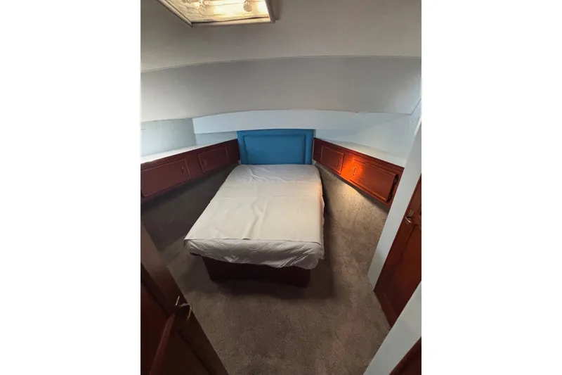 Slide: The Image of 1989 Ocean 48 Motor Yacht cabin with bed, wooden cabinets, and carpeted floor. - 12