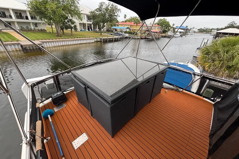 Slide: The Image of 1989 Ocean 48 Motor Yacht deck with wicker furniture, docked by waterfront homes. - 24