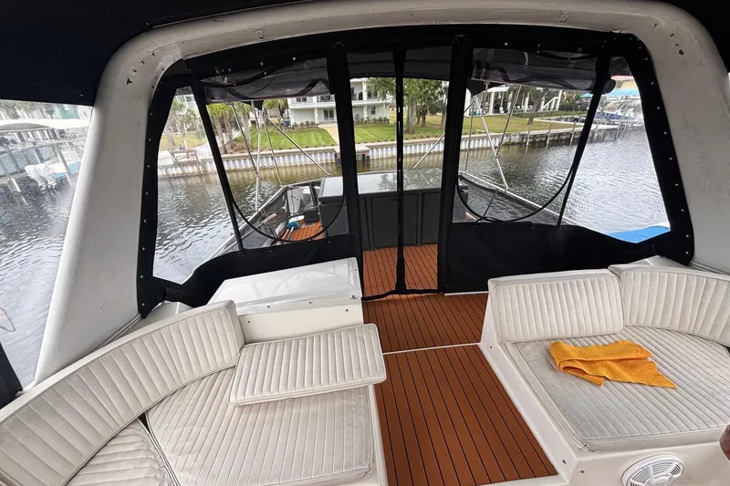 Slide: The Image of 1989 Ocean 48 Motor Yacht interior with white seating and wooden flooring, dockside view. - 25