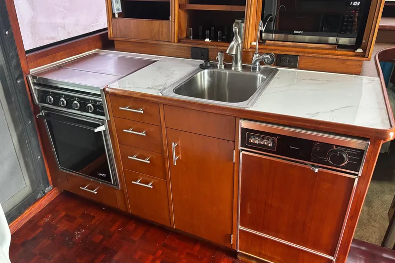 Slide: The Image of 1989 Ocean 48 Motor Yacht kitchen with stove, sink, and wooden cabinetry. - 26
