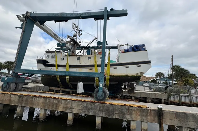 Slide: The Image of A 1992 Commercial Long Liner boat being lifted at a marina dock. - 12