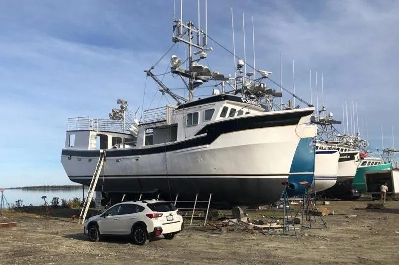 Slide: The Image of Large 1992 Commercial Long Liner boat on land, with a car parked nearby. - 2