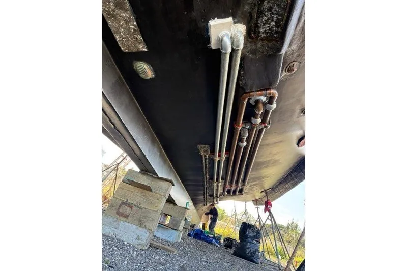 Slide: The Image of Underneath view of a 1992 Commercial Long Liner boat with visible pipes and maintenance work. - 3