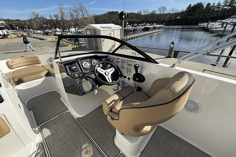 Slide: The Image of 2023 Bayliner VR5 Bowrider OB interior with helm, steering wheel, and seating by the dock. - 15
