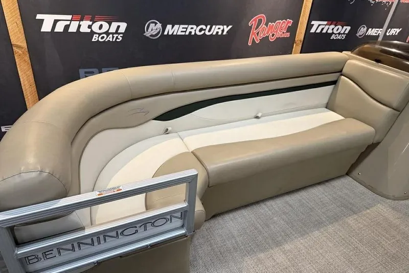 Slide: The Image of 2018 Bennington 21 SLX boat interior with beige seating and branded backdrop. - 8