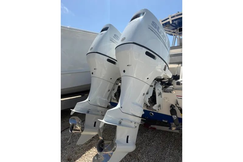 Slide: The Image of Twin outboard engines on a 2023 Sea Chaser 24 HFC boat, parked on gravel. - 23