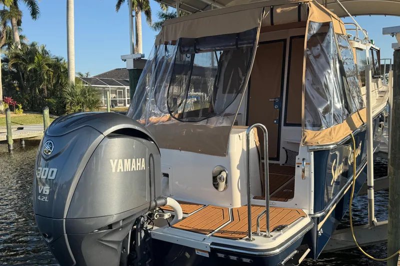 Slide: The Image of 2022 Ranger Tugs R-27 with Yamaha 300 V6 engine docked by palm trees. - 12