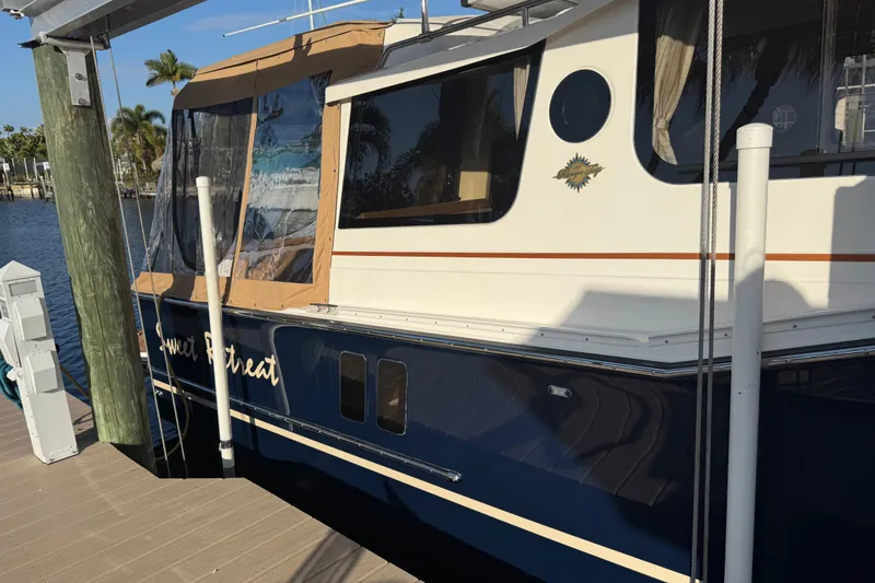 Slide: The Image of 2022 Ranger Tugs R-27 boat docked, featuring blue and white exterior with tan canopy. - 14