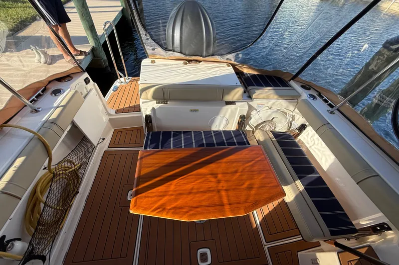 Slide: The Image of 2022 Ranger Tugs R-27 boat interior with wooden table and cushioned seating. - 15