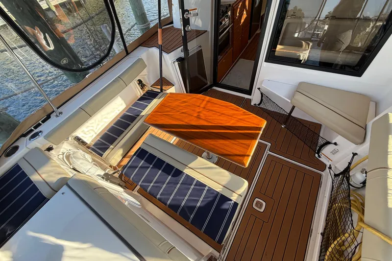 Slide: The Image of 2022 Ranger Tugs R-27 boat interior with seating and wooden table. - 16