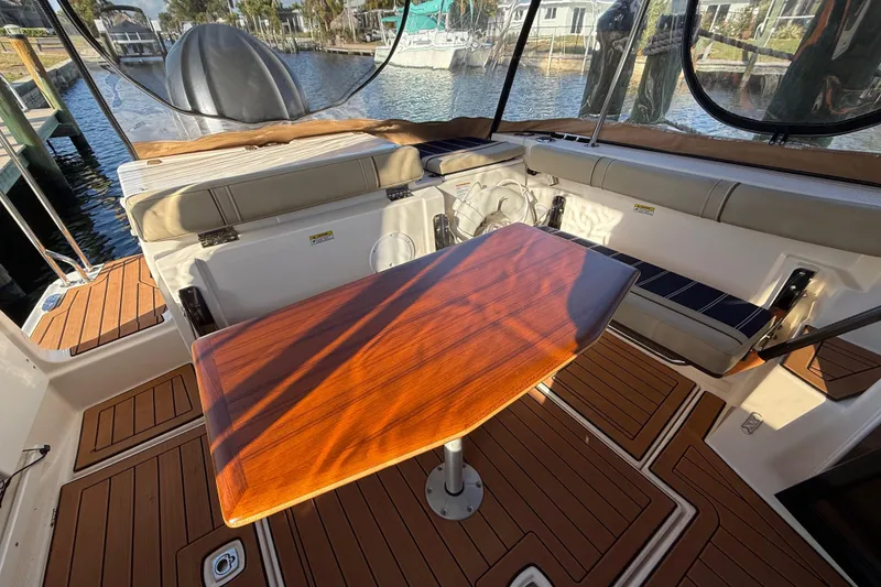 Slide: The Image of 2022 Ranger Tugs R-27 boat interior with wooden table and cushioned seating. - 17