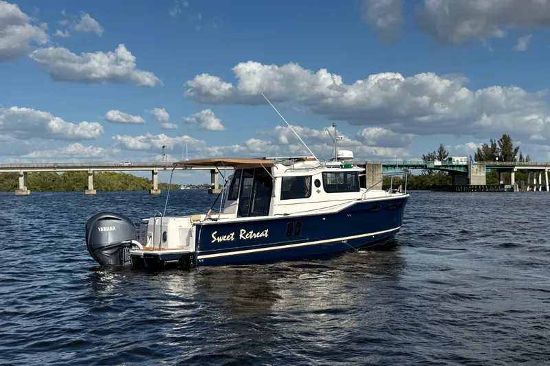 Slide: The Image of 2022 Ranger Tugs R-27 boat named "Sweet Retreat" on a sunny day near a bridge. - 2