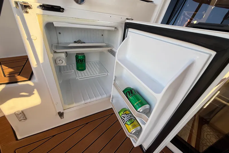 Slide: The Image of Mini fridge on 2022 Ranger Tugs R-27 boat with soda cans inside. - 23