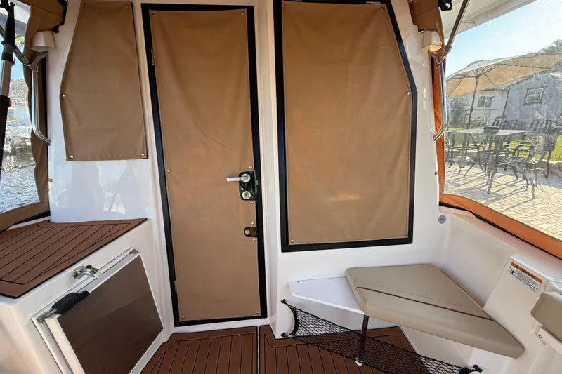 Slide: The Image of 2022 Ranger Tugs R-27 interior with tan canvas door and seating area. - 24