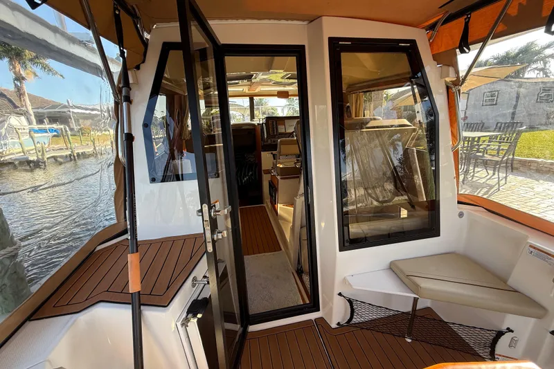 Slide: The Image of 2022 Ranger Tugs R-27 boat interior with seating and glass doors, dockside view. - 25