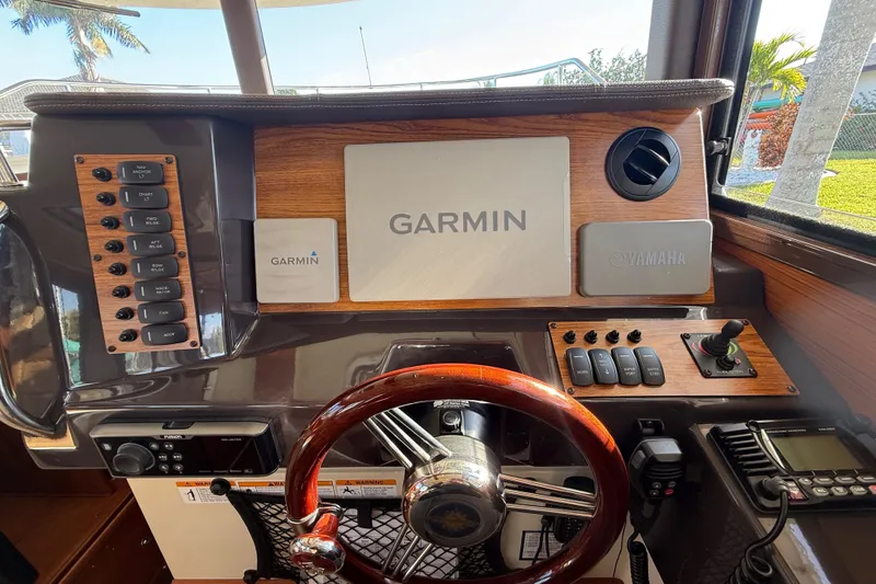 Slide: The Image of 2022 Ranger Tugs R-27 helm with Garmin and Yamaha controls, wooden accents, and steering wheel. - 33