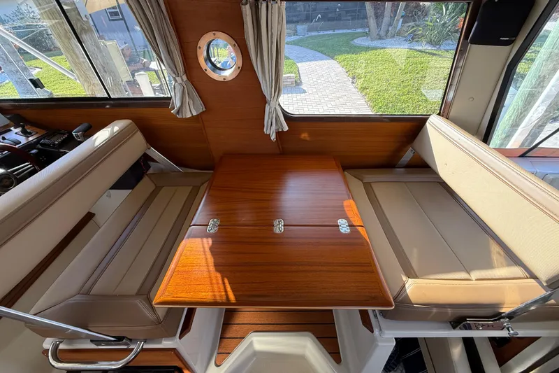 Slide: The Image of Interior of 2022 Ranger Tugs R-27 with wooden table and beige seating. - 39