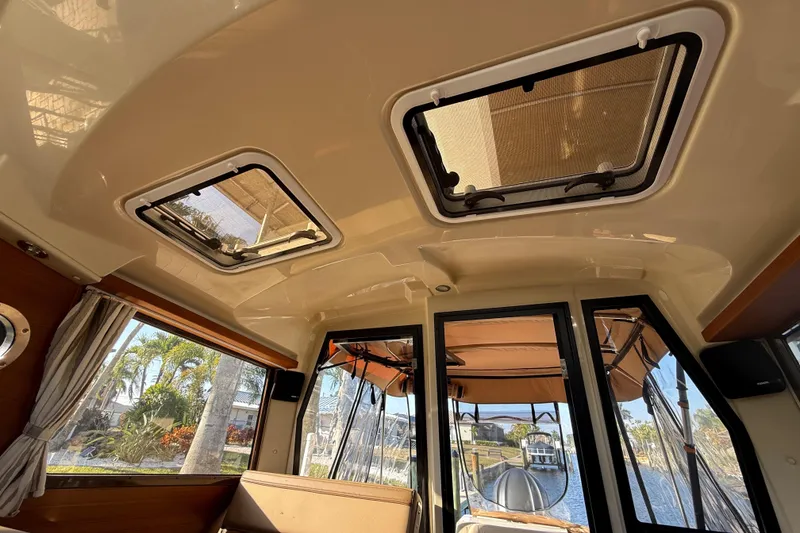 Slide: The Image of 2022 Ranger Tugs R-27 interior with sunroof, showcasing elegant design and waterfront view. - 43