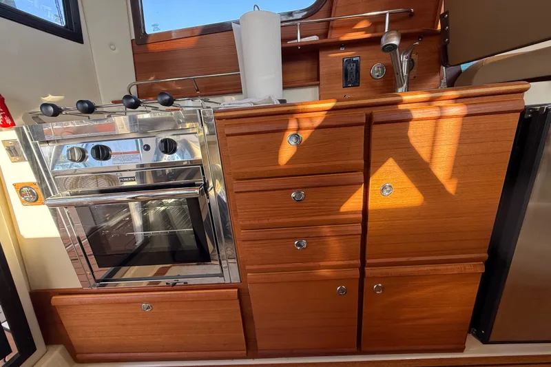 Slide: The Image of 2022 Ranger Tugs R-27 interior kitchen with wooden cabinets and stainless steel oven. - 44