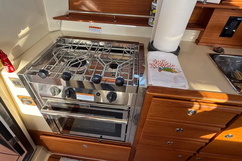 Slide: The Image of 2022 Ranger Tugs R-27 kitchen with stainless steel stove and wooden cabinetry. - 45