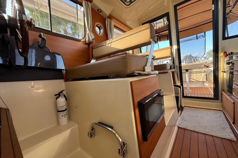 Slide: The Image of Interior of 2022 Ranger Tugs R-27 boat, featuring seating, windows, and a fire extinguisher. - 51
