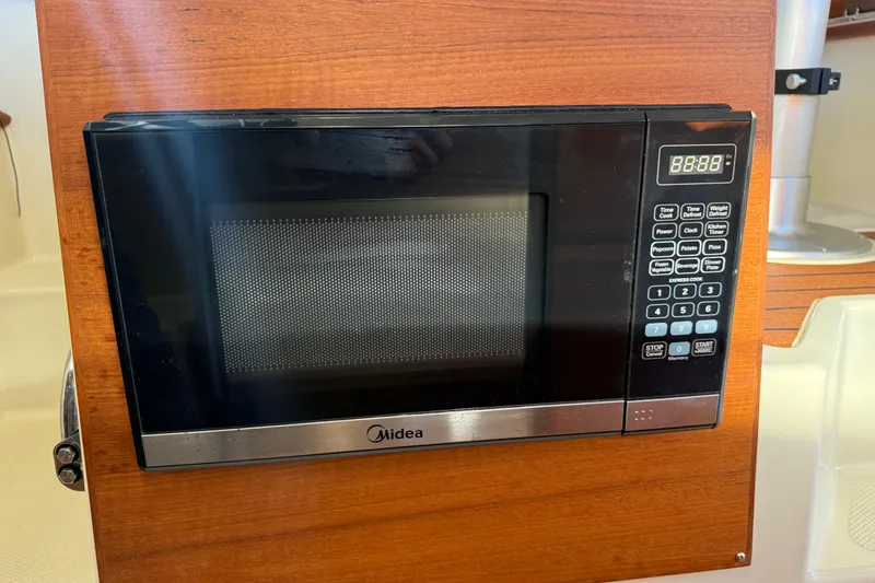 Slide: The Image of Microwave oven in 2022 Ranger Tugs R-27 boat interior, featuring wood paneling. - 52