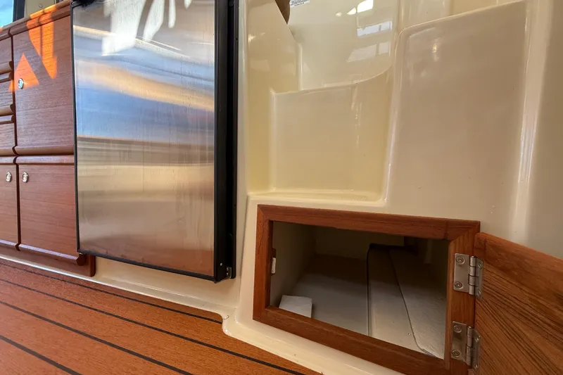 Slide: The Image of Interior of 2022 Ranger Tugs R-27, featuring wood cabinetry and stainless steel fridge. - 53