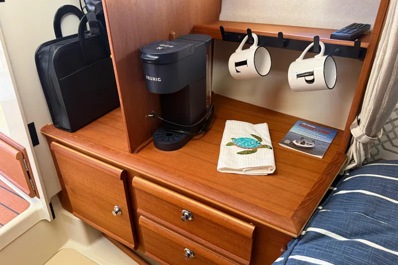 Slide: The Image of 2022 Ranger Tugs R-27 interior with Keurig, mugs, and wooden cabinetry. - 55