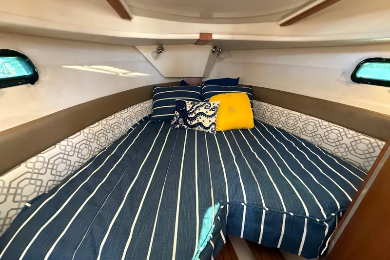 Slide: The Image of 2022 Ranger Tugs R-27 cabin interior with striped bedding and decorative pillows. - 57