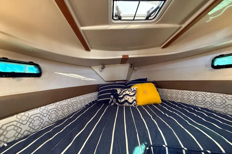 Slide: The Image of Cozy cabin interior of 2022 Ranger Tugs R-27 with striped bedding and decorative pillows. - 58