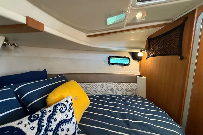 Slide: The Image of Cozy cabin interior of 2022 Ranger Tugs R-27 with striped bedding and decorative pillows. - 59