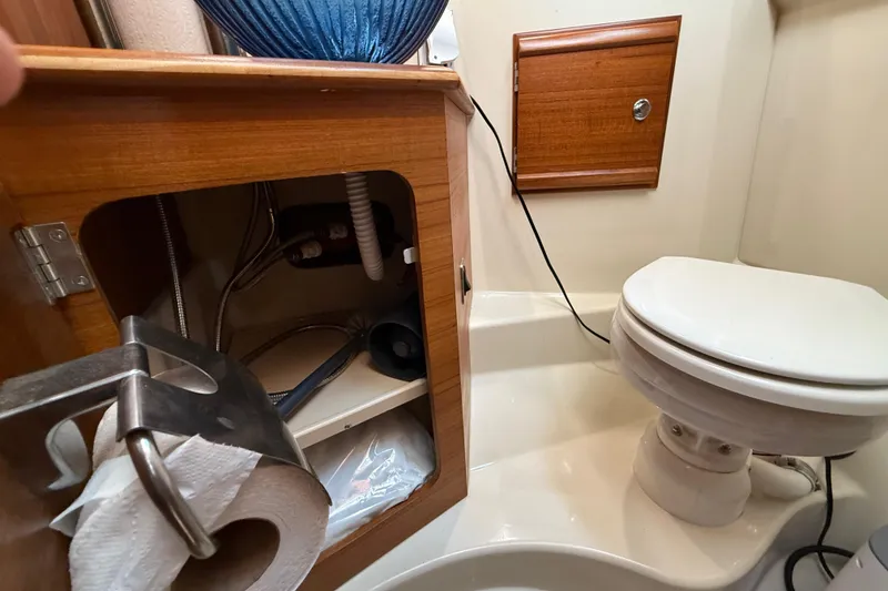 Slide: The Image of 2022 Ranger Tugs R-27 bathroom with toilet, wooden cabinet, and toilet paper holder. - 66