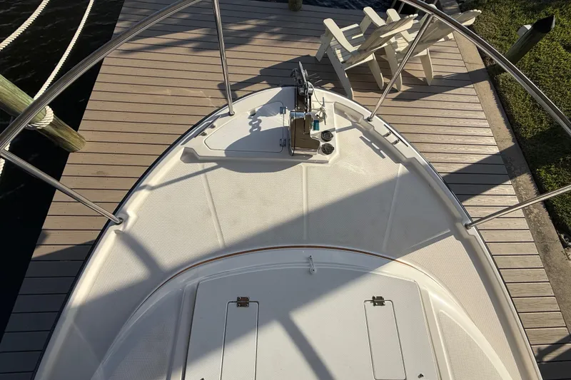 Slide: The Image of 2022 Ranger Tugs R-27 boat bow, docked with wooden deck and chairs nearby. - 69