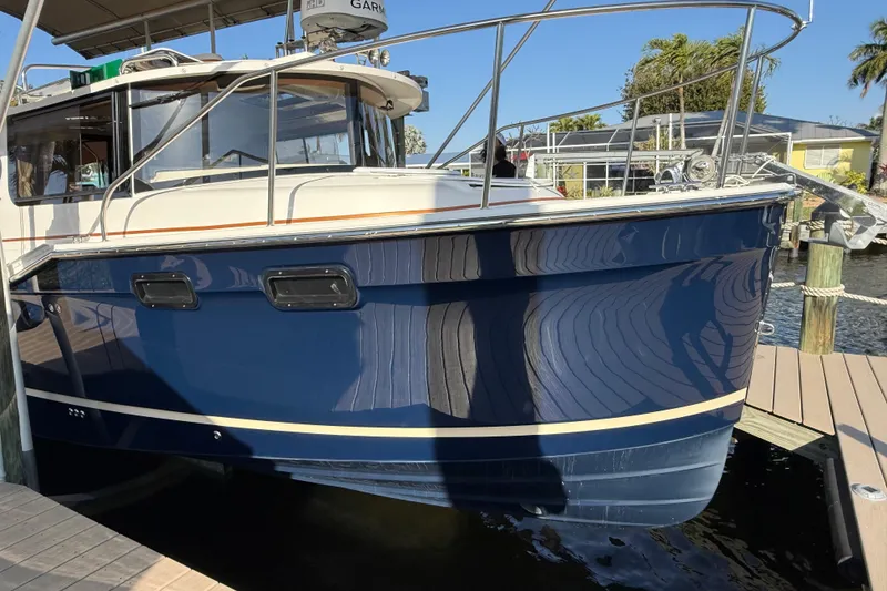 Slide: The Image of 2022 Ranger Tugs R-27 boat docked, featuring a sleek blue hull and modern design. - 75