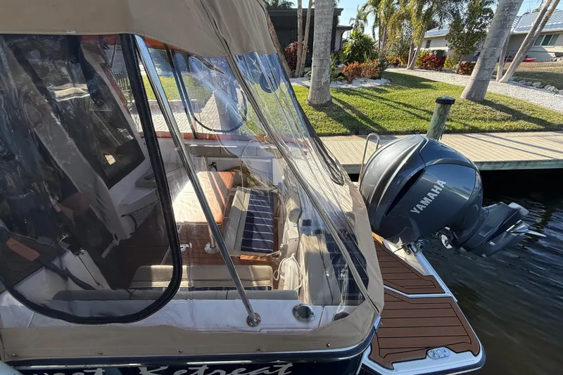 Slide: The Image of 2022 Ranger Tugs R-27 boat with Yamaha engine docked near palm trees. - 77