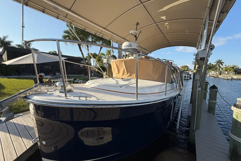 Slide: The Image of 2022 Ranger Tugs R-27 docked under canopy, surrounded by lush greenery and calm waters. - 8